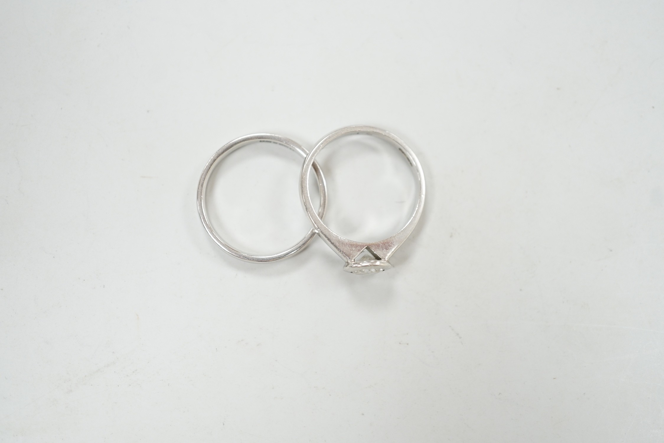 A modern platinum and collet set solitaire diamond ring, size M, gross weight 4.9 grams, together with a modern platinum wedding band, size N, 3.8 grams.